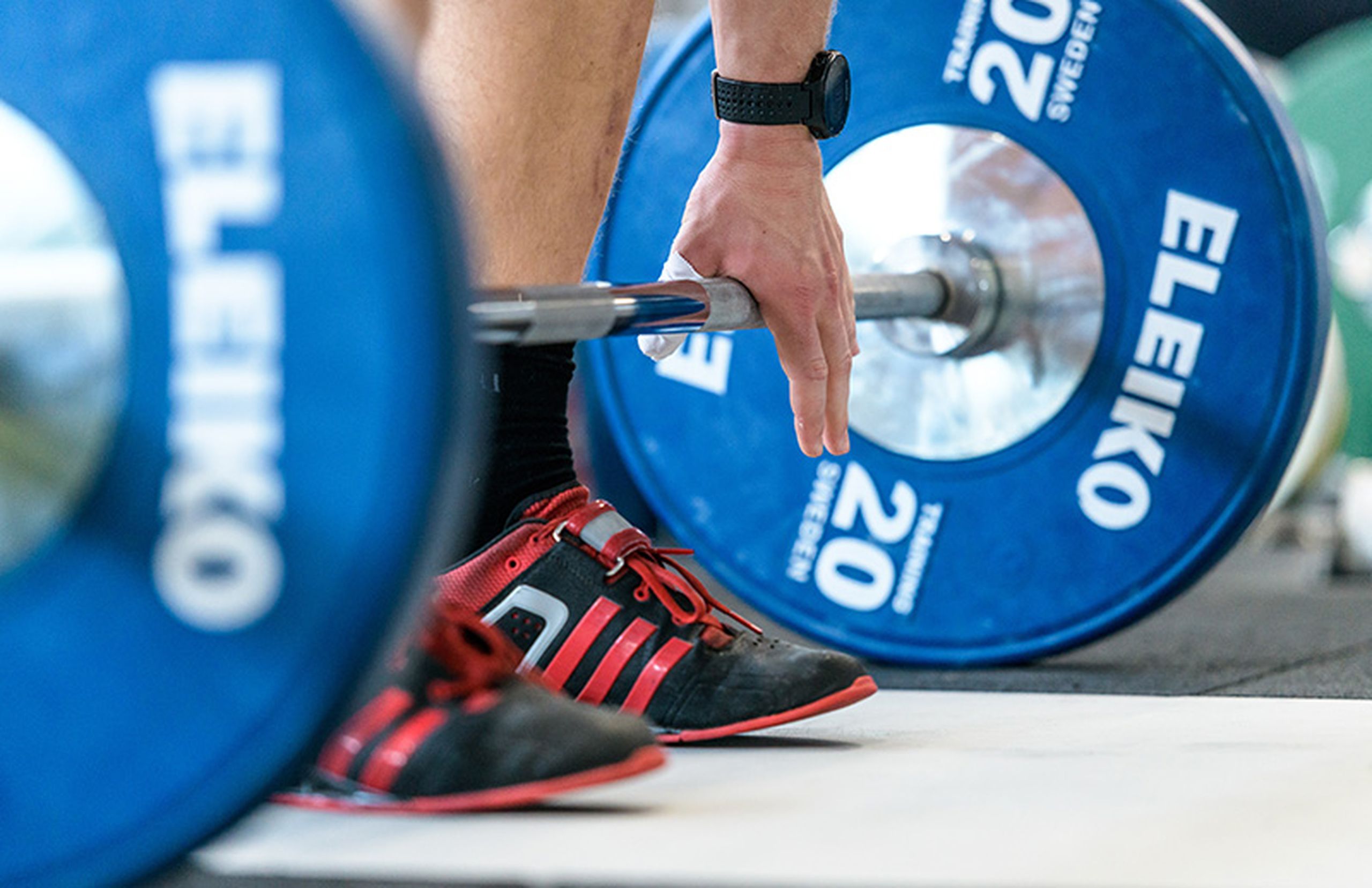 A person standing over a barbell with blue weights on it